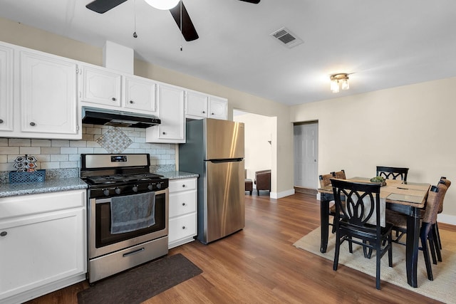 kitchen featuring visible vents, under cabinet range hood, tasteful backsplash, white cabinetry, and appliances with stainless steel finishes