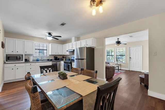 dining area with dark wood-type flooring, a ceiling fan, visible vents, and baseboards