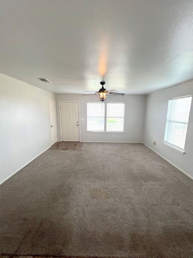 spare room featuring a textured ceiling, carpet floors, and ceiling fan