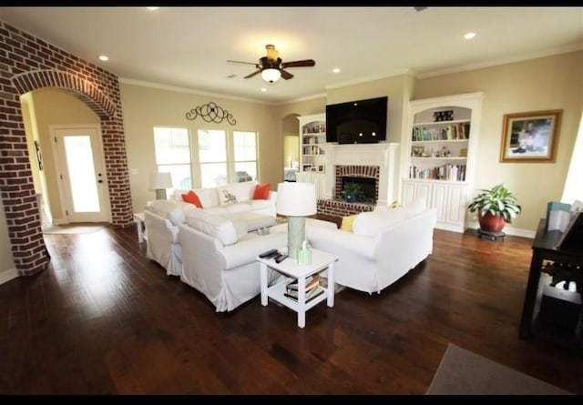 living room with a brick fireplace, ornamental molding, brick wall, ceiling fan, and dark hardwood / wood-style floors