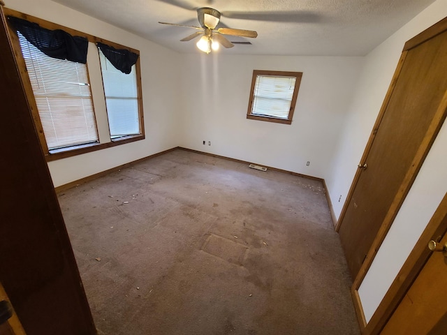 unfurnished room with ceiling fan, light carpet, and a textured ceiling