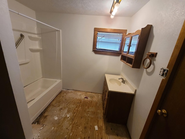 bathroom featuring vanity, wood-type flooring, a textured ceiling, and washtub / shower combination