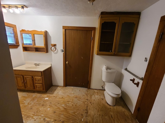 bathroom with vanity, hardwood / wood-style floors, a textured ceiling, and toilet