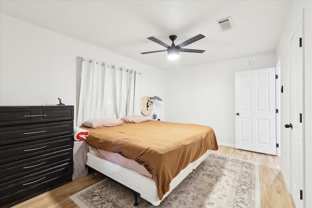 bedroom with a ceiling fan, baseboards, visible vents, and light wood finished floors