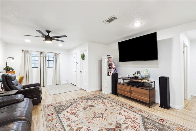 living area with light wood-style floors, visible vents, ceiling fan, and baseboards