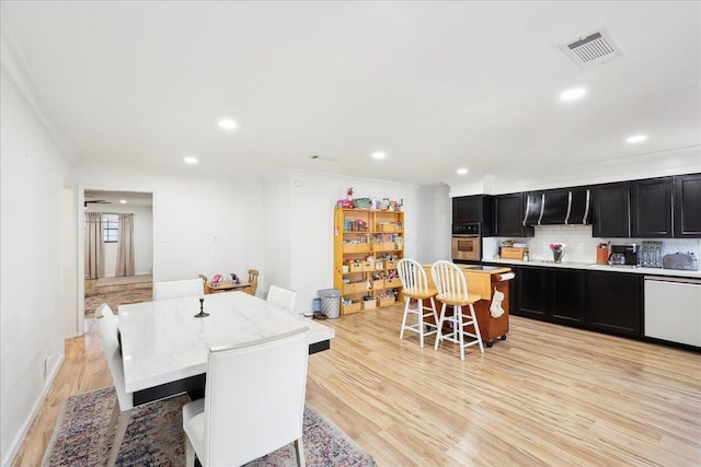 dining space with light wood-style flooring, visible vents, ornamental molding, and recessed lighting