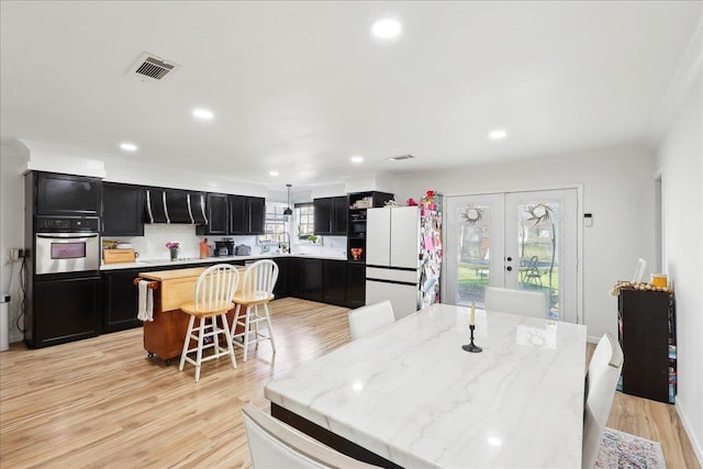 kitchen with visible vents, a kitchen island, dark cabinets, freestanding refrigerator, and stainless steel oven