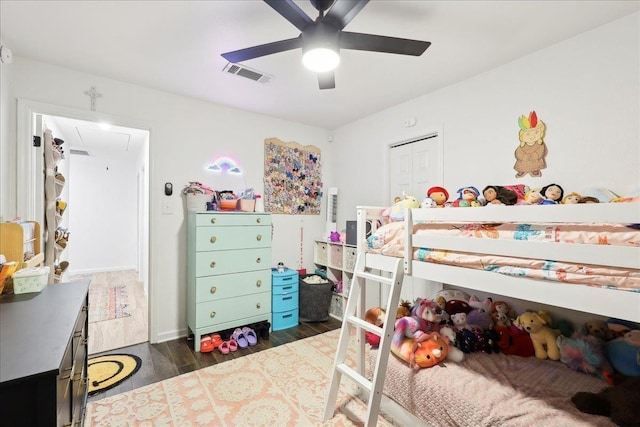 bedroom featuring a ceiling fan, attic access, visible vents, and wood finished floors