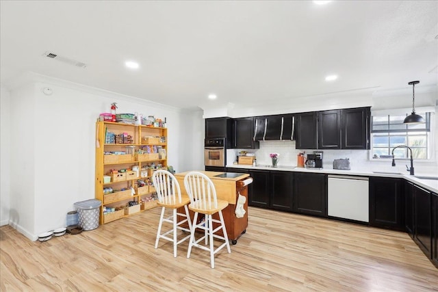 kitchen with visible vents, oven, white dishwasher, dark cabinetry, and a sink