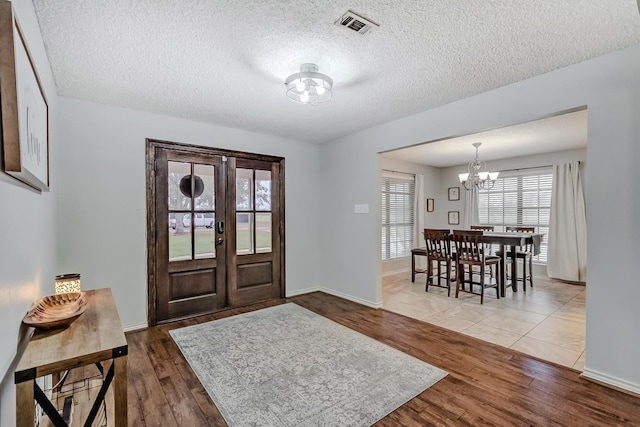 entrance foyer featuring a textured ceiling, hardwood / wood-style flooring, and an inviting chandelier