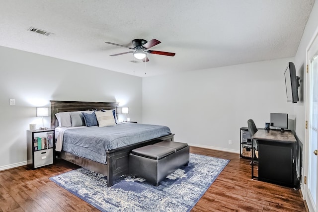 bedroom with a textured ceiling, dark hardwood / wood-style flooring, and ceiling fan