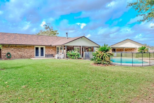 rear view of property with french doors, a fenced in pool, and a lawn