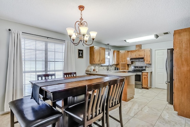 kitchen featuring appliances with stainless steel finishes, tasteful backsplash, sink, pendant lighting, and a chandelier