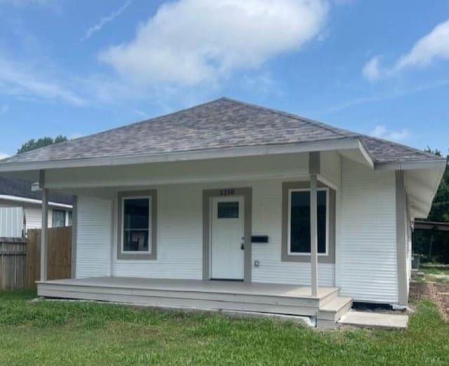 rear view of property featuring a porch and a lawn