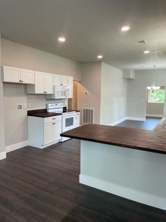 kitchen with white cabinetry, dark hardwood / wood-style floors, a notable chandelier, and white appliances