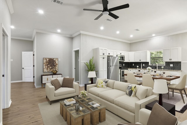 living room with light hardwood / wood-style flooring, ceiling fan, and crown molding