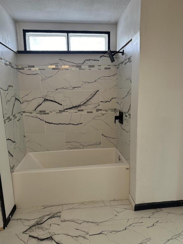 bathroom with tiled shower / bath and a textured ceiling