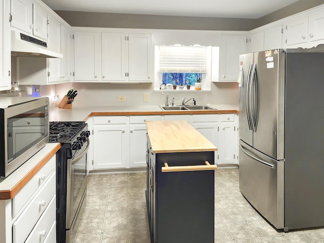 kitchen with white cabinets, sink, butcher block countertops, a kitchen island, and stainless steel appliances