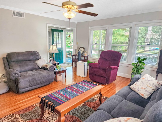 living room featuring wood-type flooring, ceiling fan, and crown molding