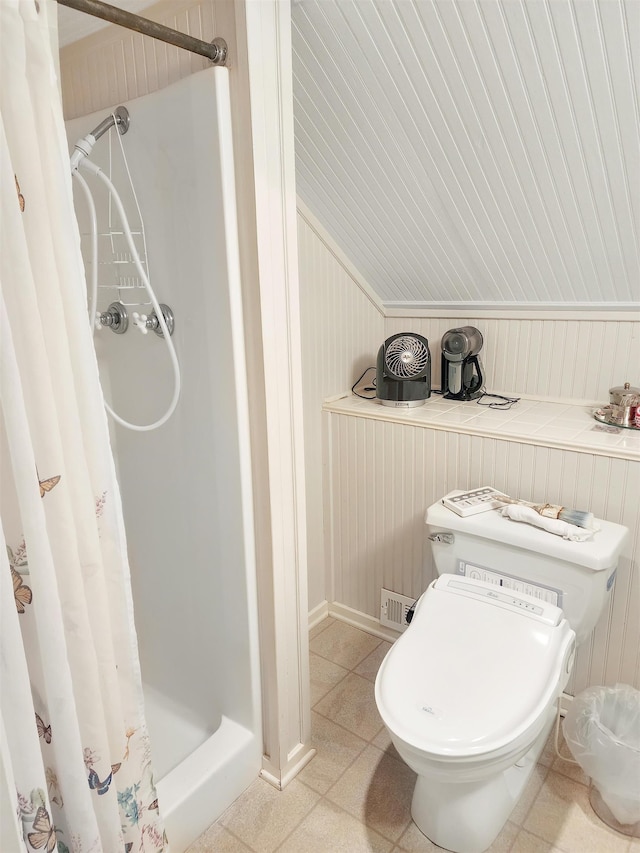 bathroom featuring ornamental molding, lofted ceiling, walk in shower, and wooden walls