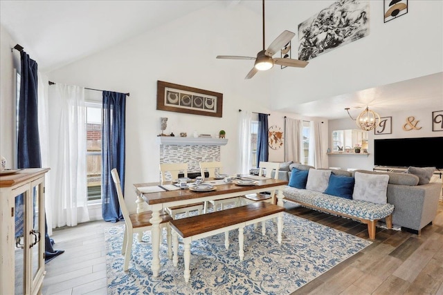 living area featuring ceiling fan with notable chandelier, high vaulted ceiling, and light wood finished floors