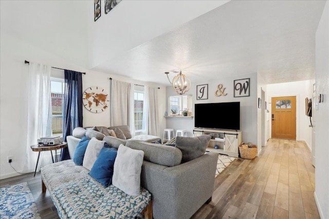 living area featuring light wood-style flooring, baseboards, and a chandelier