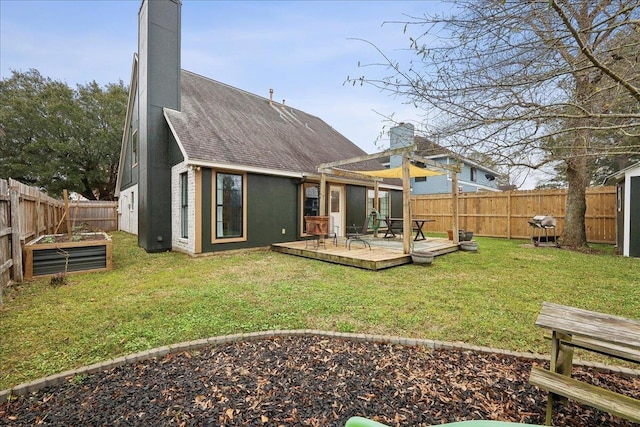 back of property featuring roof with shingles, a vegetable garden, a fenced backyard, a chimney, and a deck