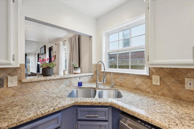 kitchen with plenty of natural light, white cabinets, and a sink