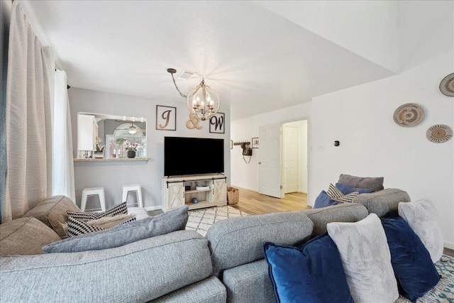 living area featuring an inviting chandelier, light wood-style floors, visible vents, and baseboards