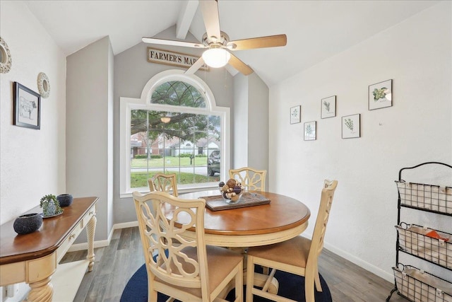 dining space featuring baseboards, a ceiling fan, wood finished floors, and vaulted ceiling with beams