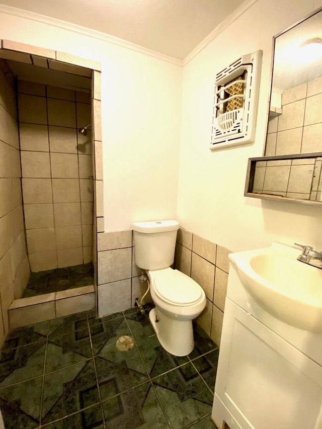 bathroom with tile patterned floors, tiled shower, toilet, vanity, and ornamental molding