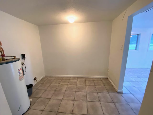 washroom featuring water heater, light tile patterned floors, and a textured ceiling