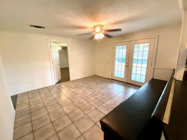 spare room featuring french doors, a textured ceiling, light tile patterned floors, and ceiling fan