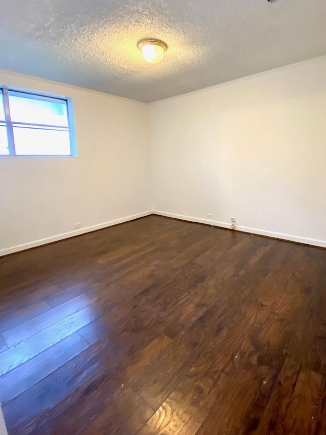 empty room with dark hardwood / wood-style floors and a textured ceiling