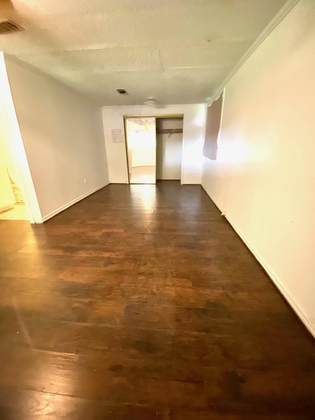 empty room featuring dark hardwood / wood-style floors, ornamental molding, and a textured ceiling