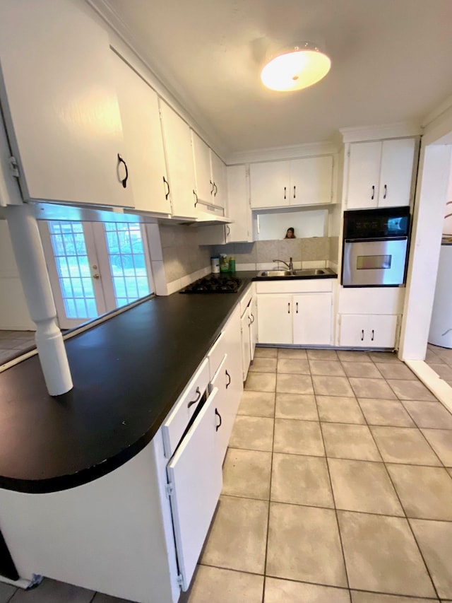 kitchen featuring oven, white cabinetry, sink, and light tile patterned floors