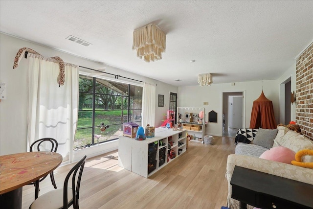 1210 Nottingham Ln, Beaumont, TX 77706 - living room with light wood-style floors, a textured ceiling, and a chandelier