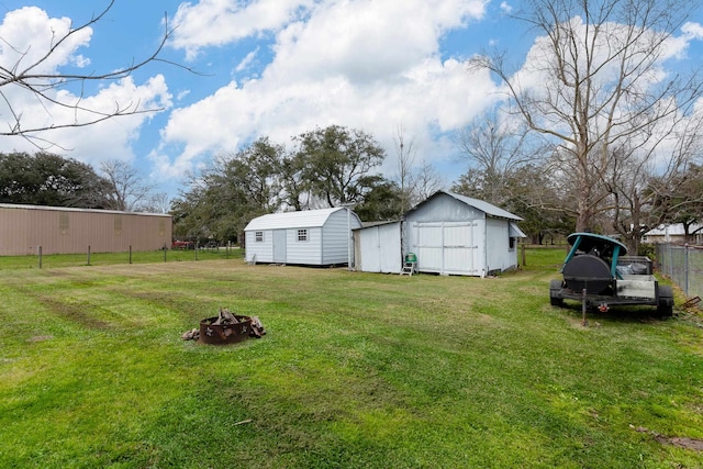 view of yard with a storage unit, fence, an outbuilding, and an outdoor fire pit