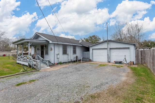 view of front facade featuring board and batten siding, fence, covered porch, a garage, and driveway