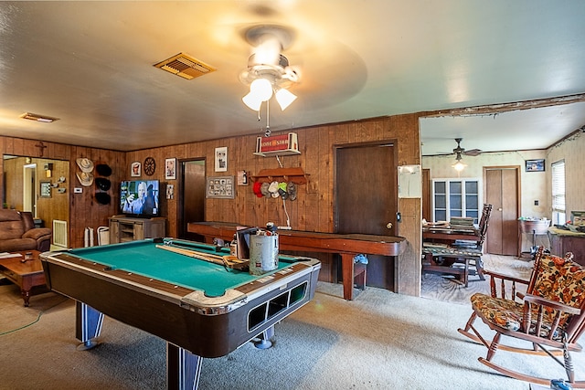 game room featuring wooden walls, visible vents, a ceiling fan, and carpet