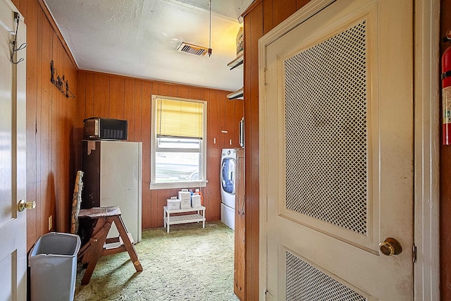 corridor featuring washer / dryer, wooden walls, and visible vents