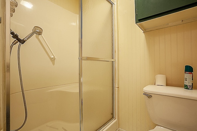 full bath with toilet, wood walls, and a shower stall