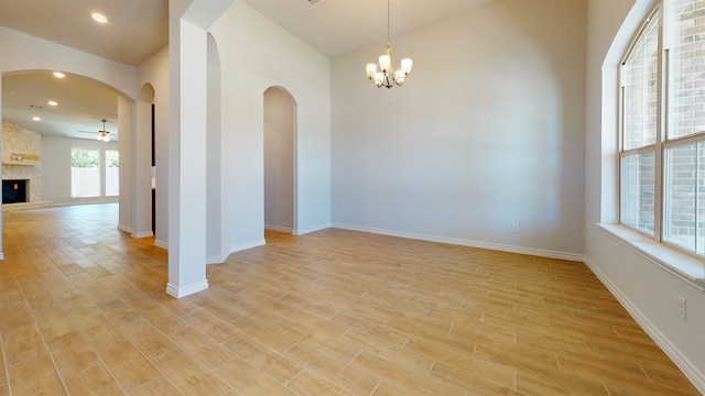 225 Sycamore Ct, Lumberton, TX 77657 - empty room featuring light wood finished floors, ceiling fan, a chandelier, arched walkways, and a stone fireplace