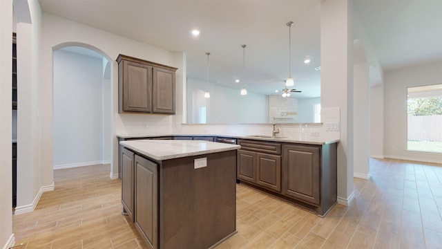 225 Sycamore Ct, Lumberton, TX 77657 - kitchen featuring decorative backsplash, light wood-type flooring, a center island, ceiling fan, and arched walkways