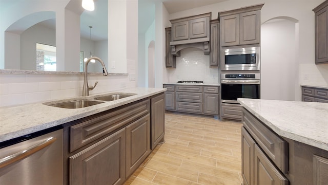 225 Sycamore Ct, Lumberton, TX 77657 - kitchen with stainless steel appliances, tasteful backsplash, arched walkways, and light stone countertops