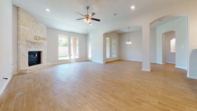 225 Sycamore Ct, Lumberton, TX 77657 - unfurnished living room featuring ceiling fan, a stone fireplace, light wood finished floors, and arched walkways