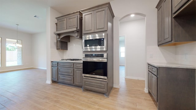 225 Sycamore Ct, Lumberton, TX 77657 - kitchen featuring appliances with stainless steel finishes, a chandelier, arched walkways, and tasteful backsplash