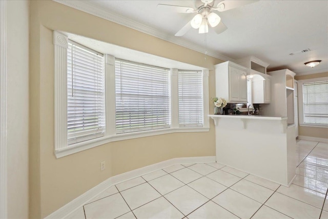 5210 Ada Ave, Beaumont, TX 77708 - kitchen with light tile patterned floors, a ceiling fan, white cabinetry, baseboards, and crown molding