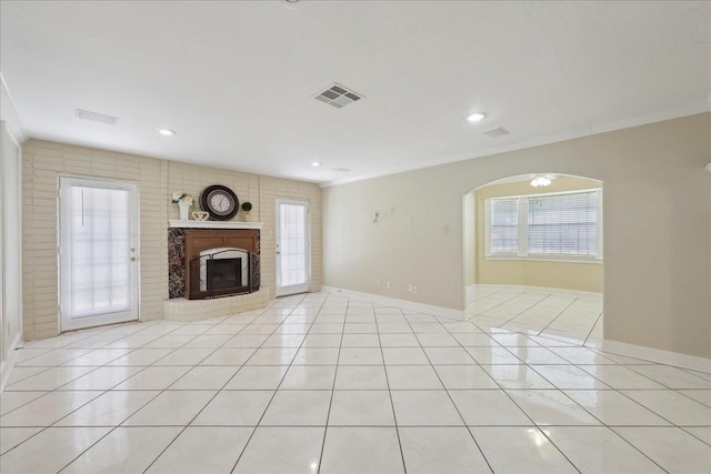 5210 Ada Ave, Beaumont, TX 77708 - unfurnished living room featuring light tile patterned floors, arched walkways, a brick fireplace, ornamental molding, and baseboards