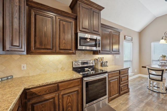 kitchen with appliances with stainless steel finishes, vaulted ceiling, decorative backsplash, baseboards, and dark brown cabinetry